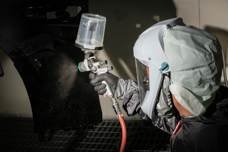 Spray painter applying paint in booth