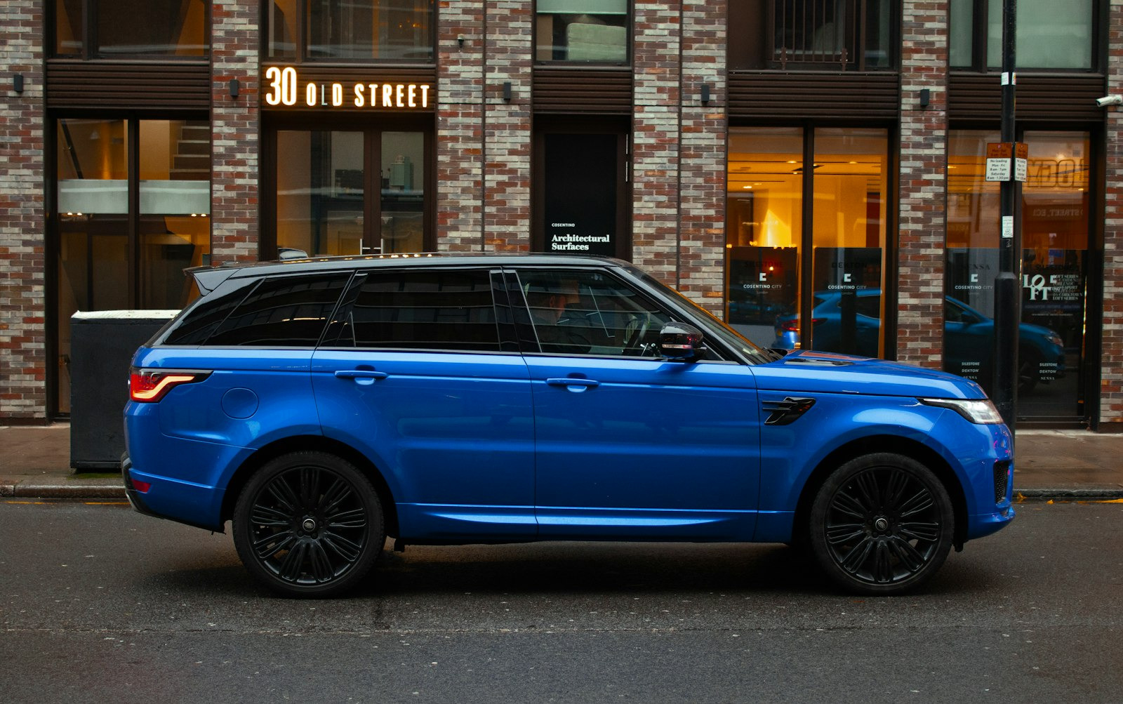 Side profile of a blue Range Rover Sport parked on a city street